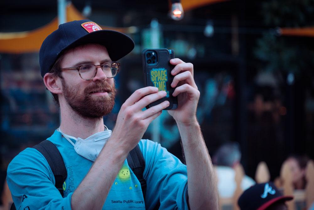 Todd Little sports a new Space-Time Adventure Tours sticker on his Walkie-Talkie Time Machine (iPhone) - looking off camera and smiling.